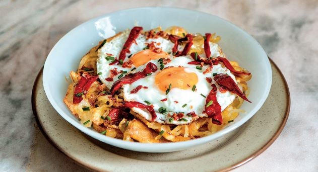 Huevos rotos con cebolla caramelizada, crujiente de jamón y pimientos del Piquillo